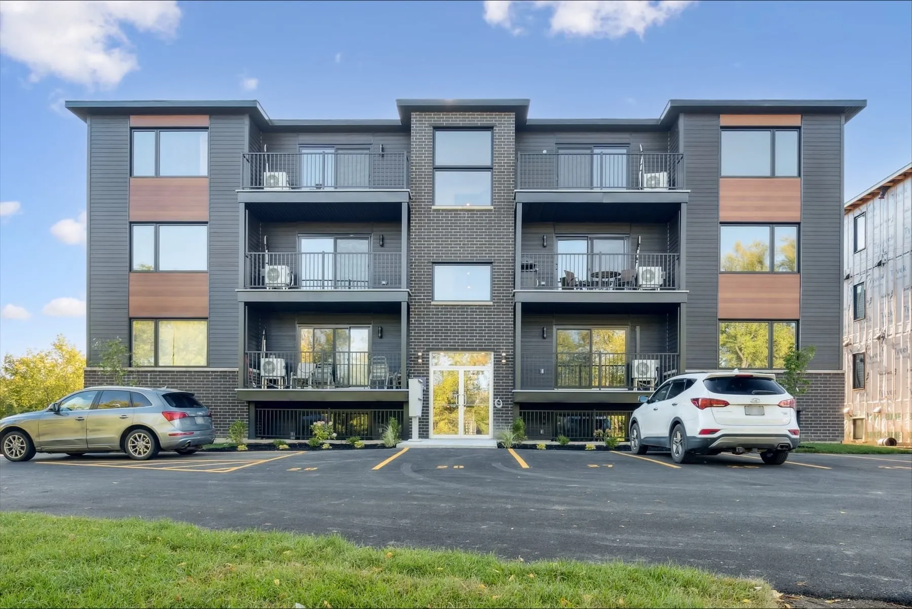 Façade d'un des deux bâtiments Henderson : quatre niveaux, brique au centre, revêtement foncé et panneaux de bois