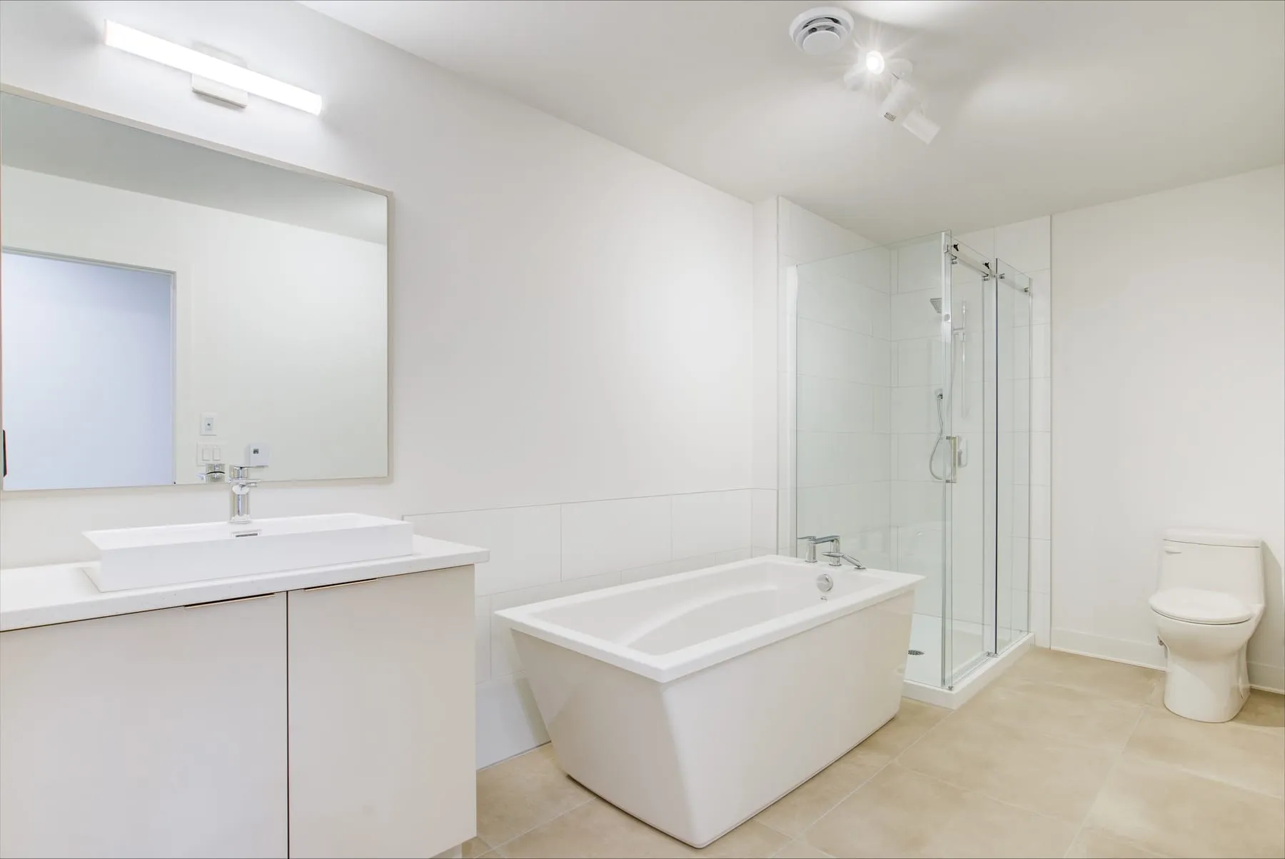 Salle de bain avec bain autoportant, douche vitrée et vanité claire