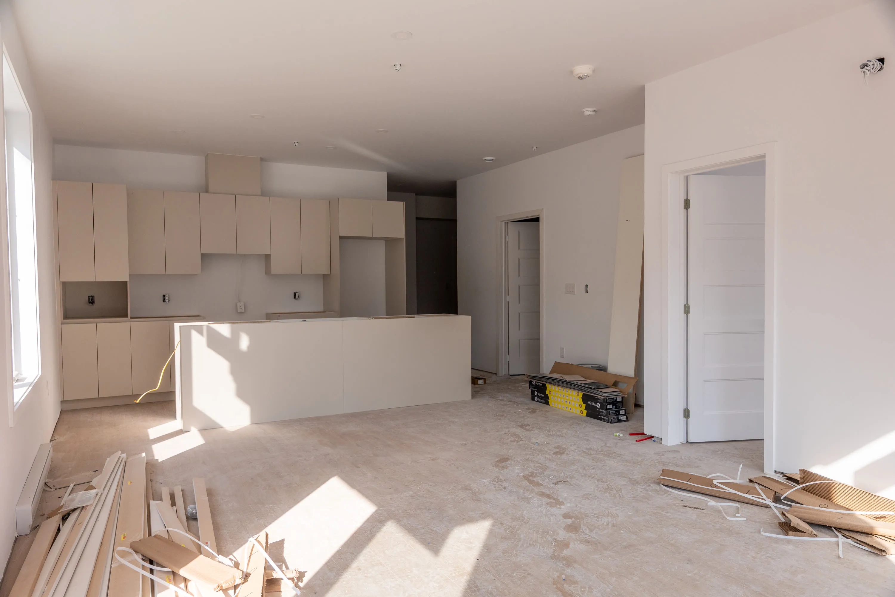 Aire ouverte d'un logement en chantier : cuisine avec îlot et armoires posées